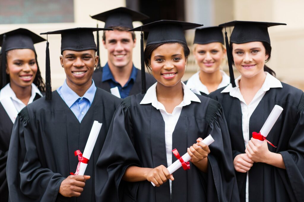 Young, interracial college graduates posing with their caps, gowns and degrees in hand.